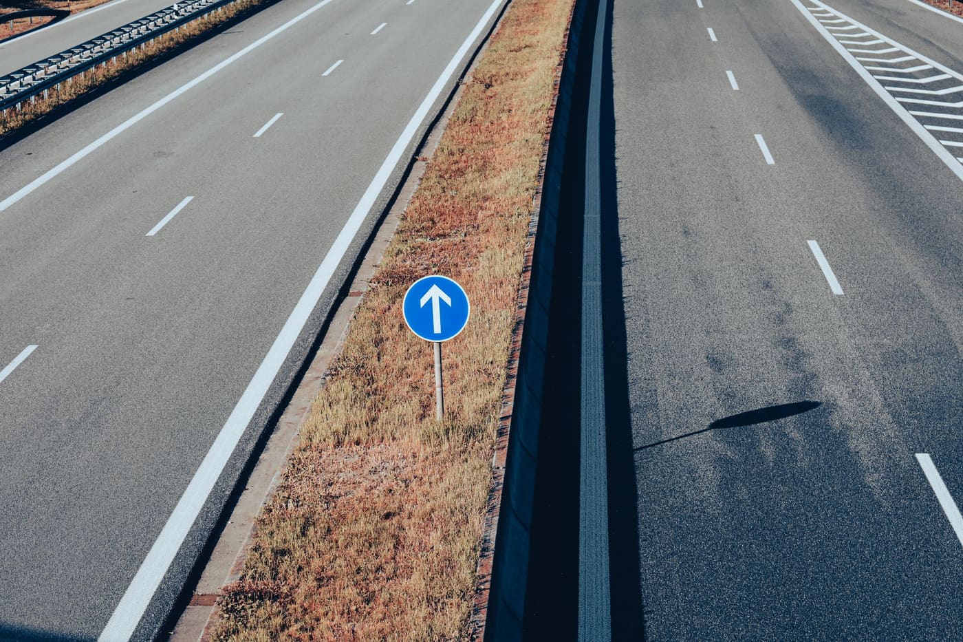 Aerial view of an empty divided highway with a white arrow sign beside the lanes